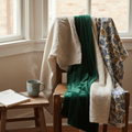 Sunlit studio corner with linen, velvet, boucle, and hand-printed fabric swatches draped over a wooden chair